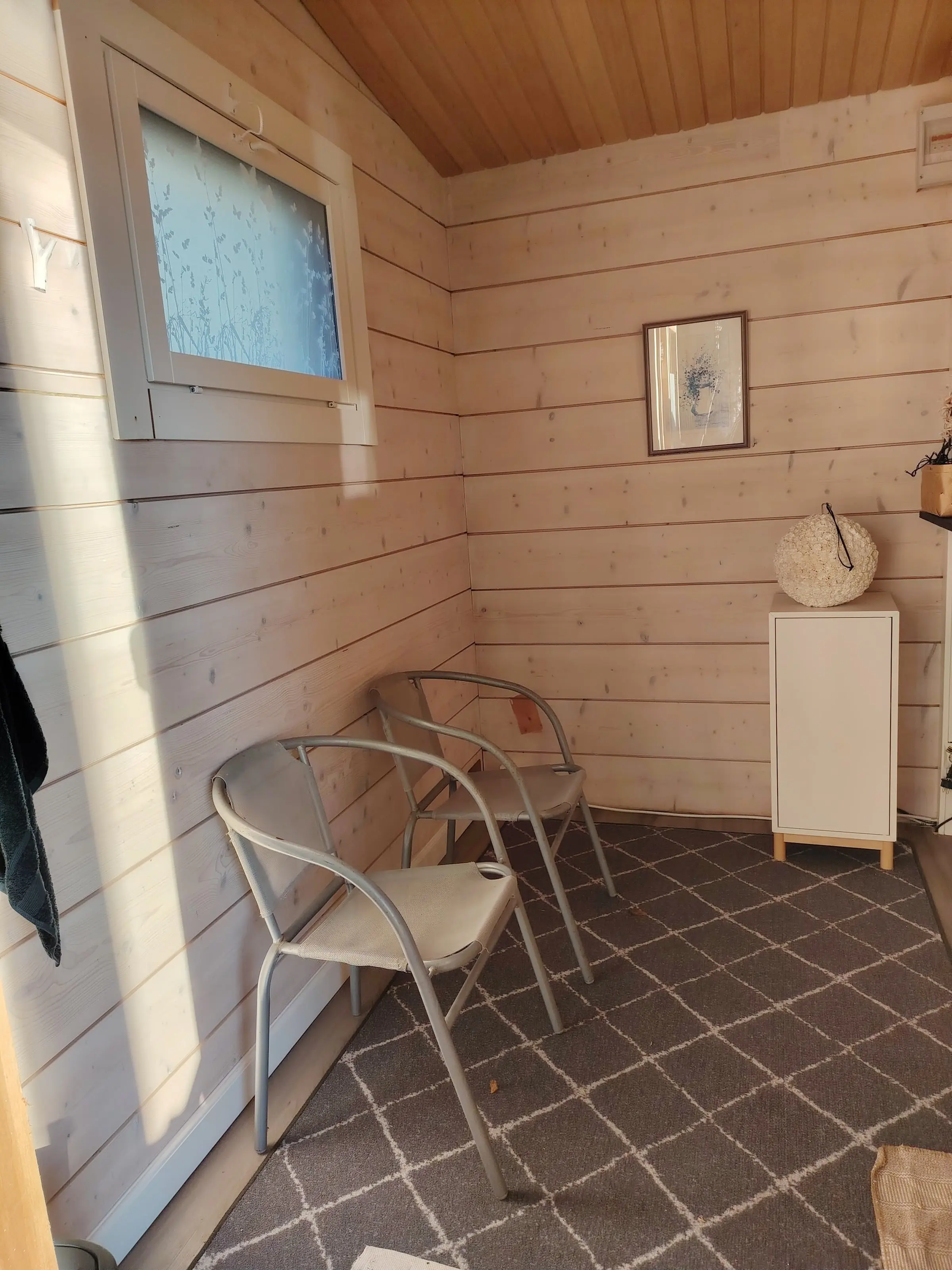 The dressing room, with light wood panelling, two chairs, a small cabinet and a frosted window.