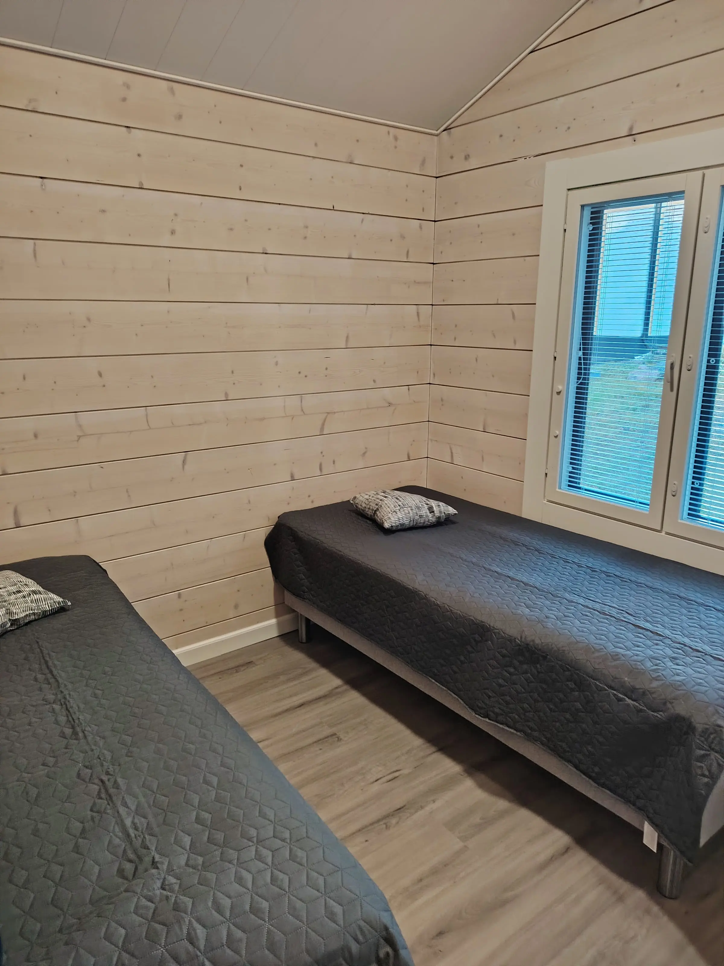 A bedroom with two single beds and a window.